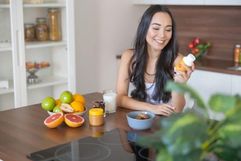 Frau sitzt in der Küche mit Obst und Nahrungsergänzung, Symbol für ausgewogene Ernährung und vitamin c 1000 im Alltag